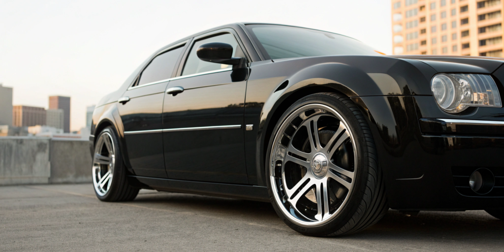 A black Chrysler 300 with aftermarket rims and tires for sale.